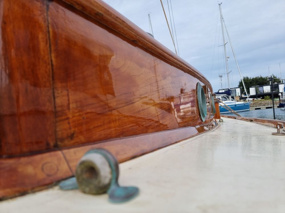Varnished cabin side with bronze portholes beside a painted deck