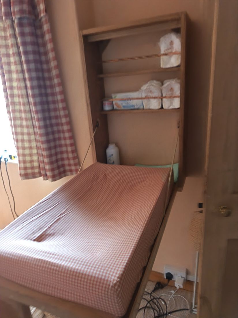 The changing table in use, with nappies and supplies held on the shelves behind copper rails