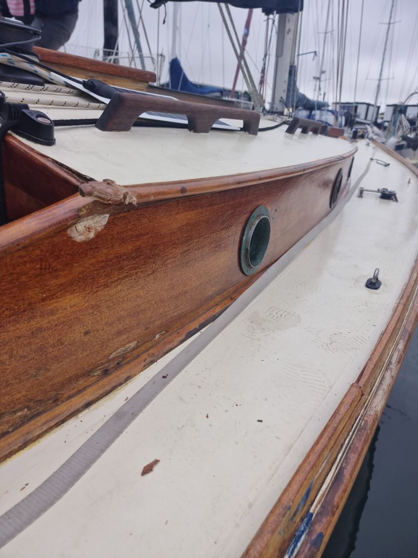 Folkdance's cabin side and side deck after the collision, with the coaming corner smashed and the toerail damaged