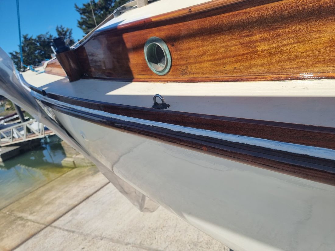The repaired toerail and cabin side varnished to a high gloss above the cream topsides