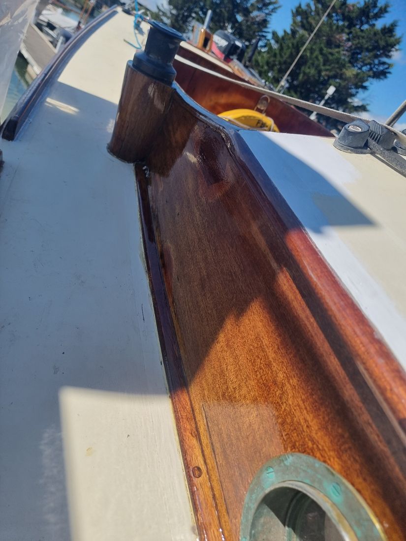 Looking along the repaired coaming, freshly varnished to a deep gloss beside the winch