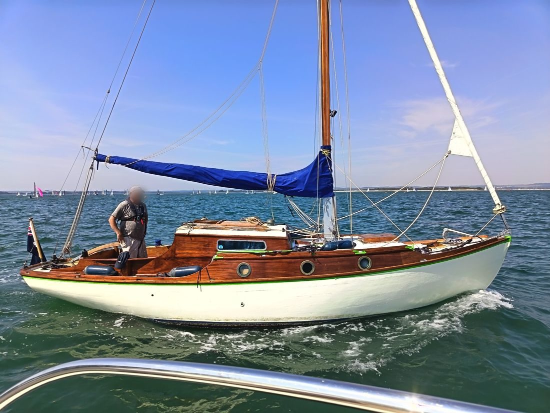 Hightime under way in the Solent, her varnished coachroof and white topsides catching the sun