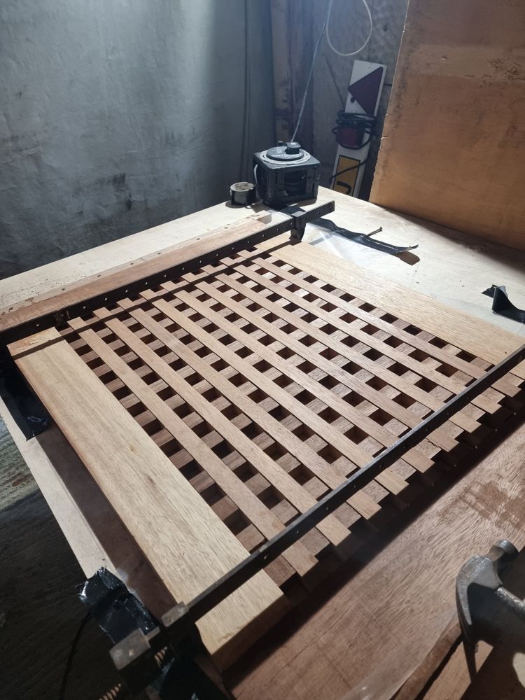 Cockpit grating being glued up, interlocking slats held in sash cramps on the bench