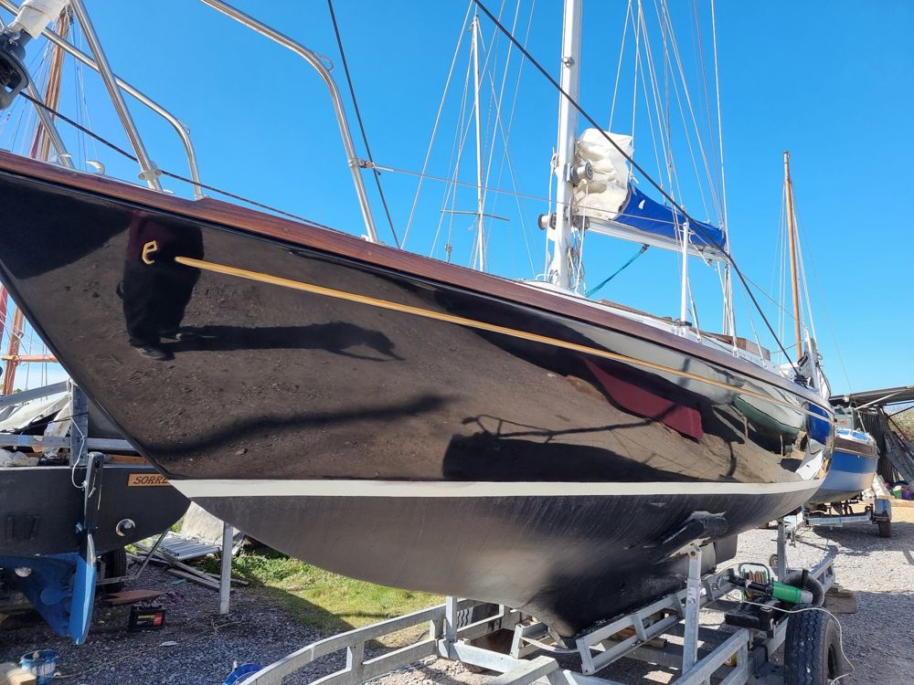 Black Bess's black topsides with a gilded cove line and varnished rubbing strake, on her trailer