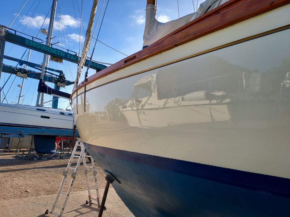 Roamer's cream topsides and varnished toerail glowing in the sun, the boat hoist behind