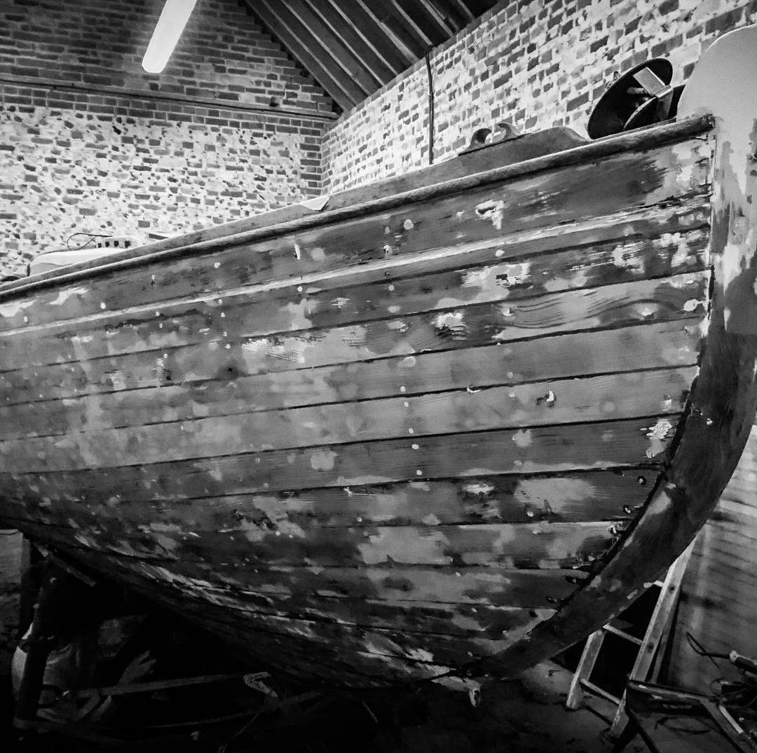 Petrina's hull in the workshop with old paint partly stripped back to bare planking