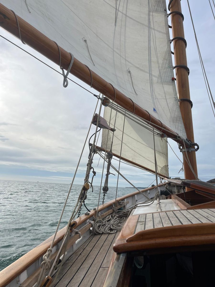 View along Rhoda's deck under the varnished boom and mainsail, laid deck and skylight below