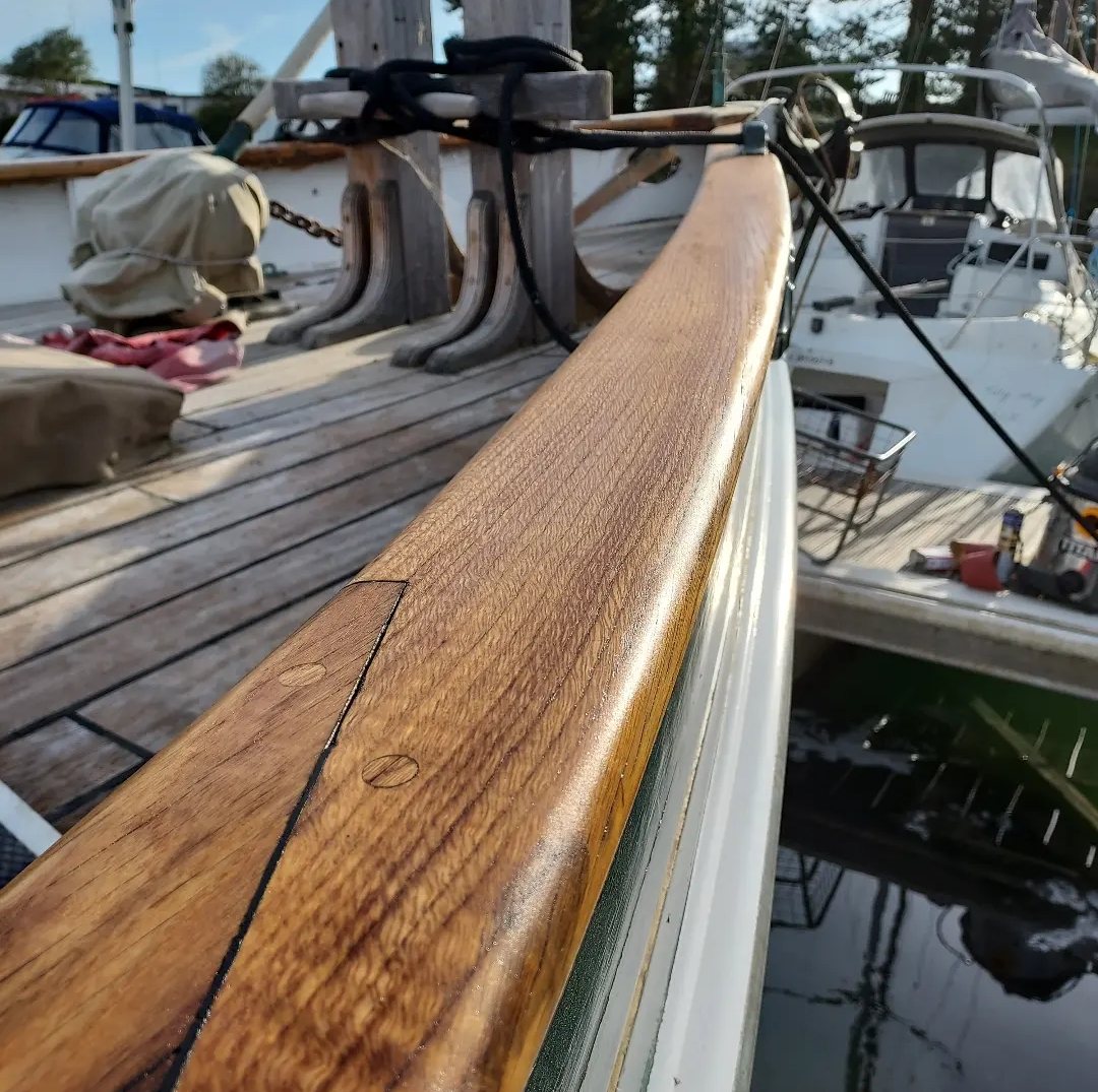 Rhoda's capping rail freshly oiled, the grain glowing beside her bitts and laid deck