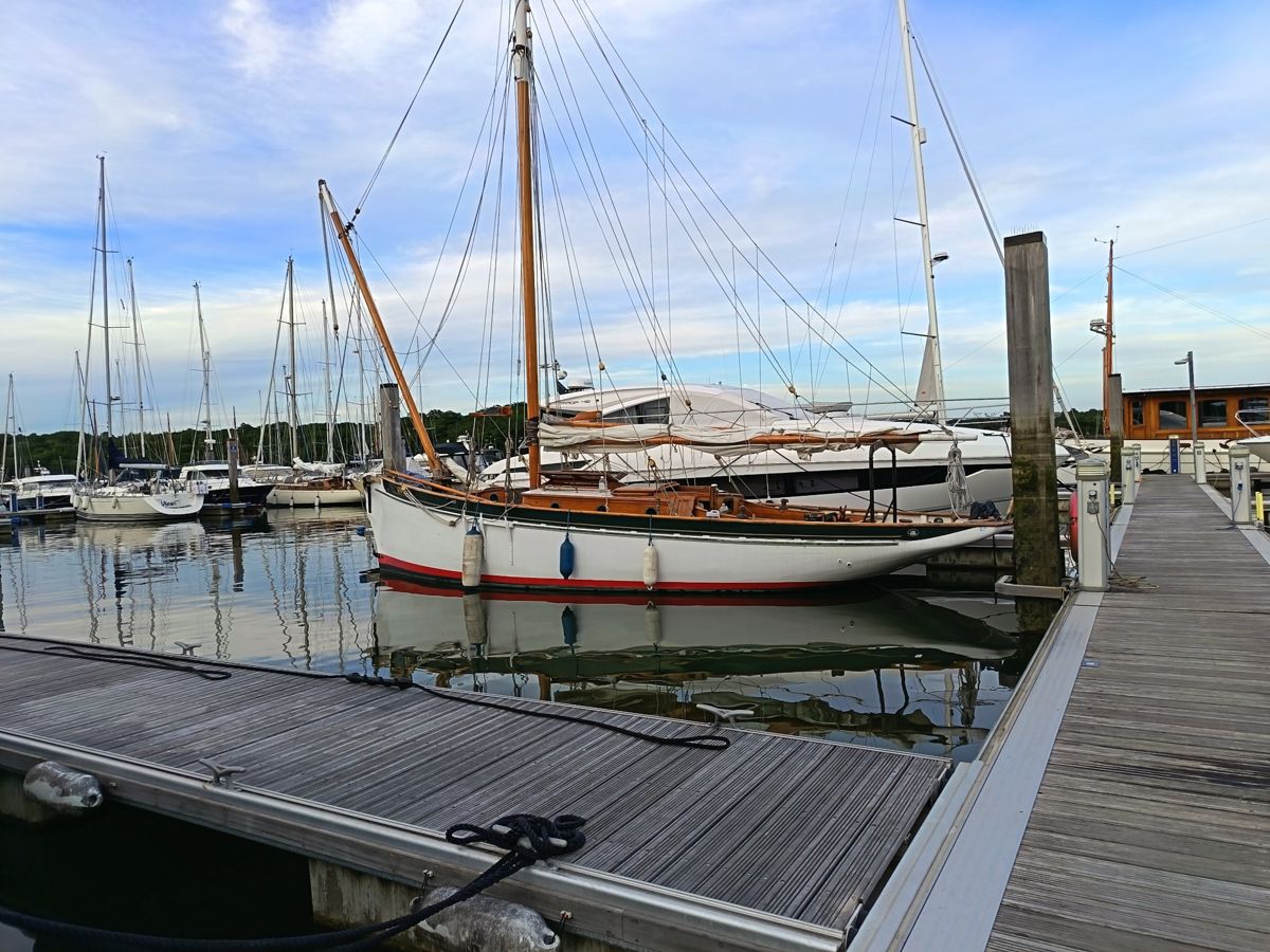 Rhoda, a 1937 Boston smack, on her pontoon in a marina with the new mast and gaff rig