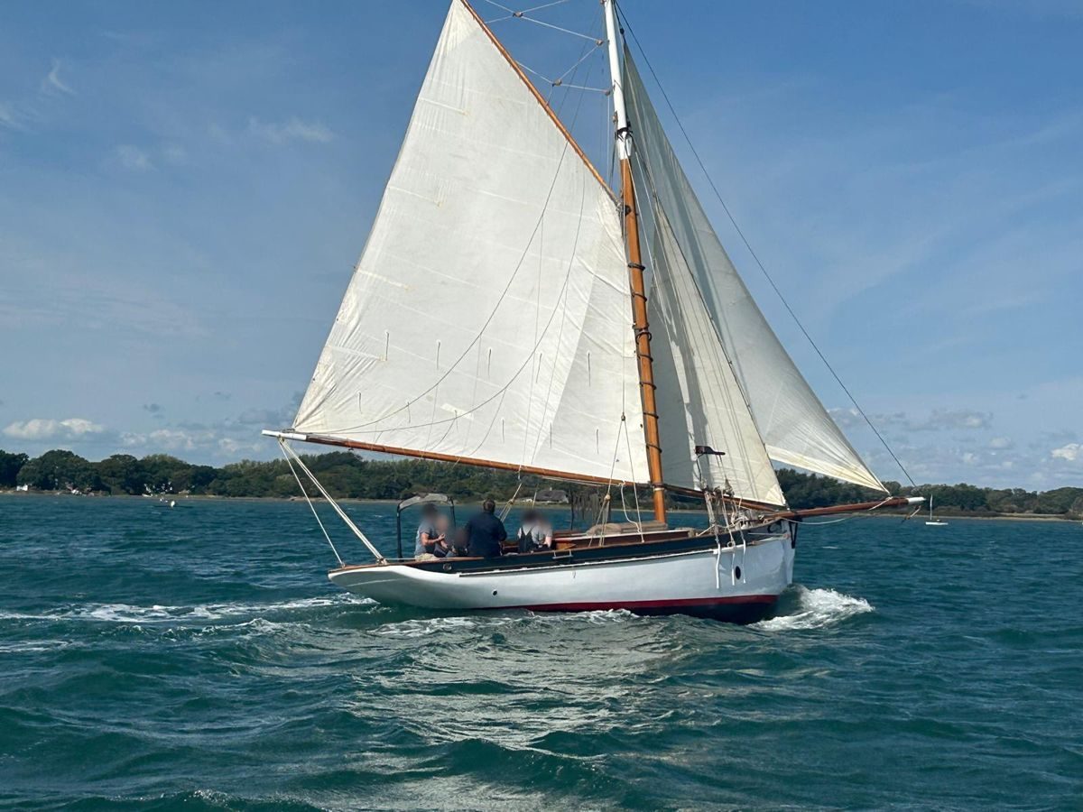 Rhoda under full sail in the harbour with crew aboard
