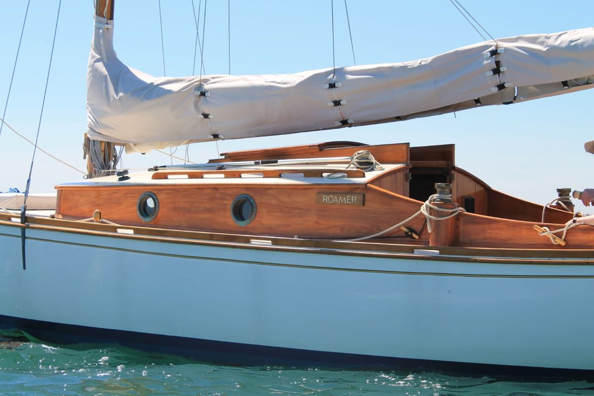 Close view of Roamer's varnished coachroof side with bronze portlights and her name board
