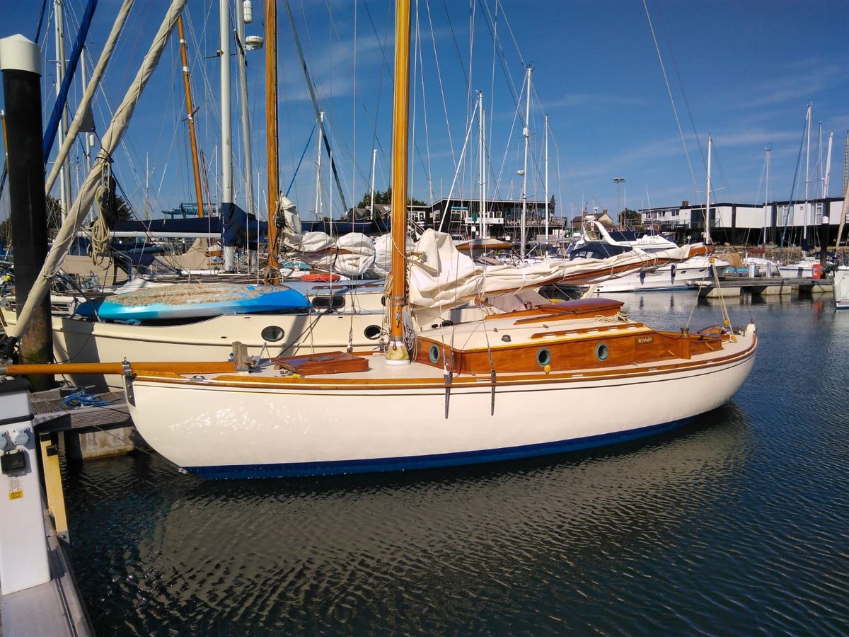 Roamer afloat on her pontoon in the marina, cream topsides and varnished coachroof gleaming in the sun