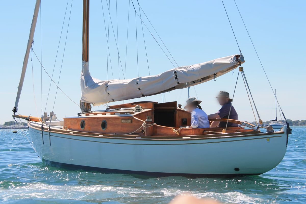 Roamer out on the water with two people in the cockpit, mainsail furled under its cover