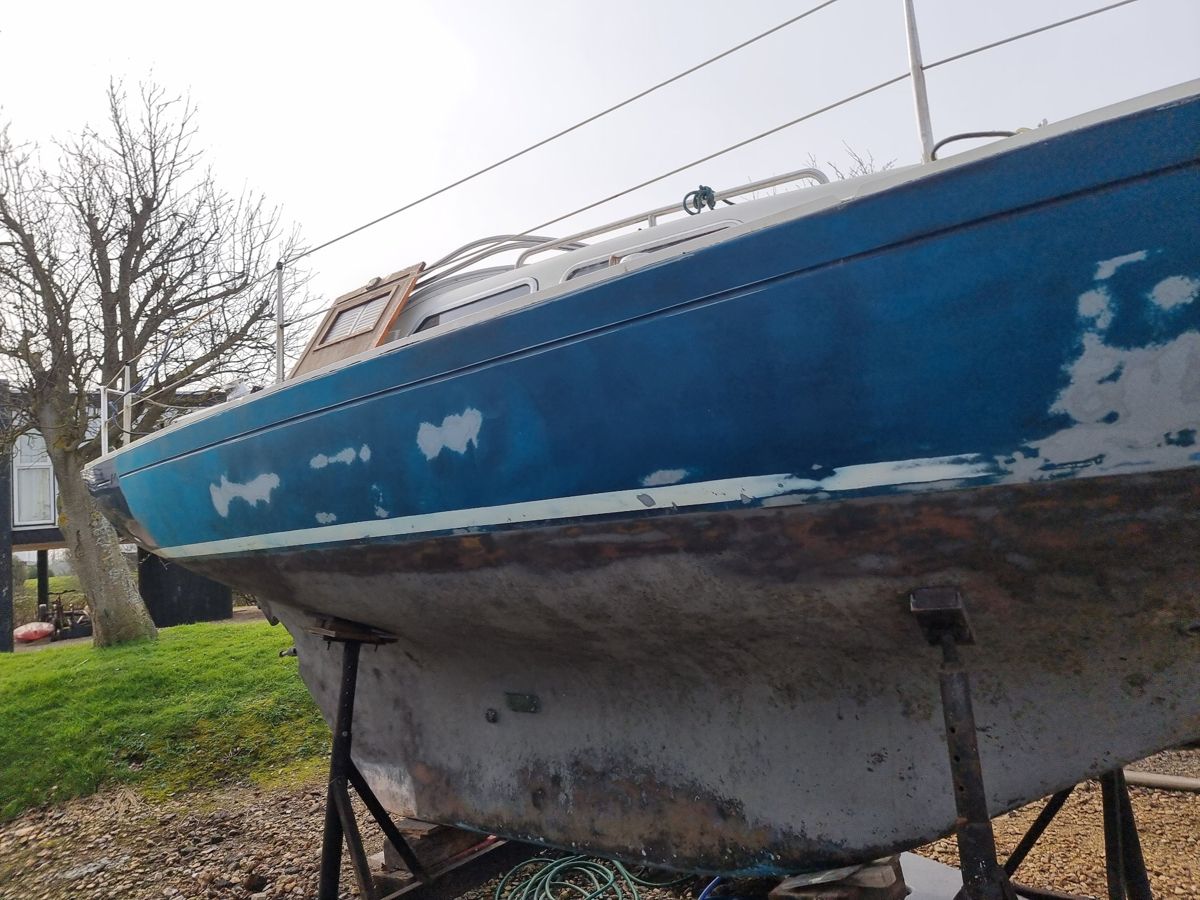 Sempre en Giro before work: faded blue topsides patched with filler and a worn, stained bottom