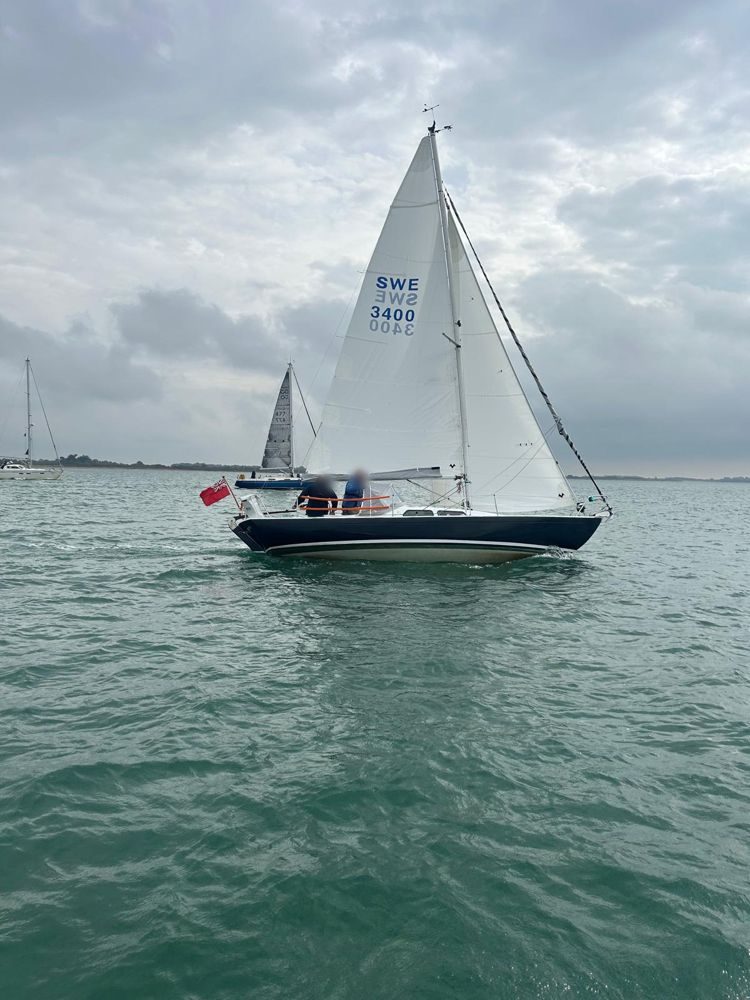 Sempre en Giro sailing in the harbour with her navy hull, sail number SWE 3400