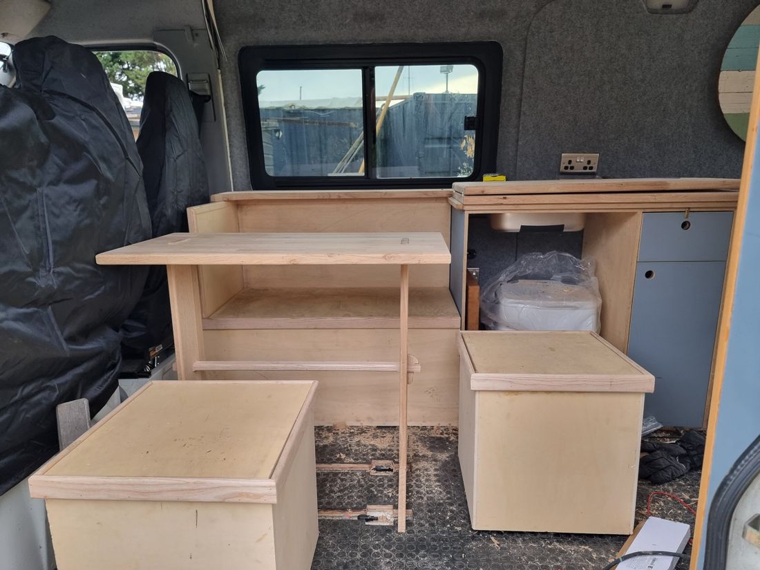 Bare ply carcasses, seat boxes and an oak table base set out in the empty van