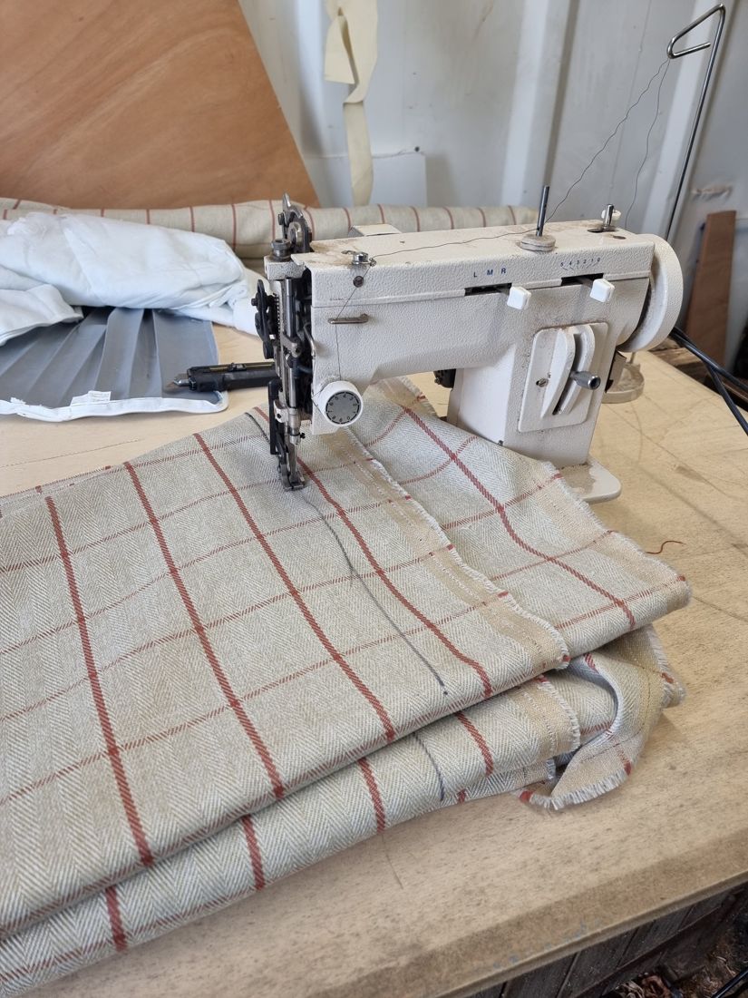 Checked herringbone fabric being sewn into cushions on a heavy-duty sewing machine