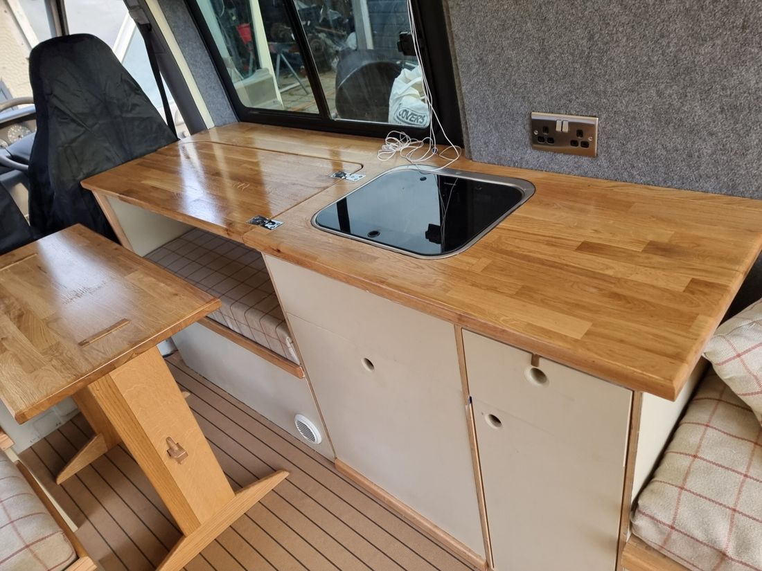 Finished galley with oiled oak worktop, hinged leaf, flush sink and painted cupboard doors