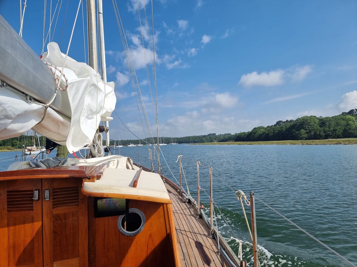 Looking forward along Zircon's teak deck and varnished doghouse as she motors up a wooded river