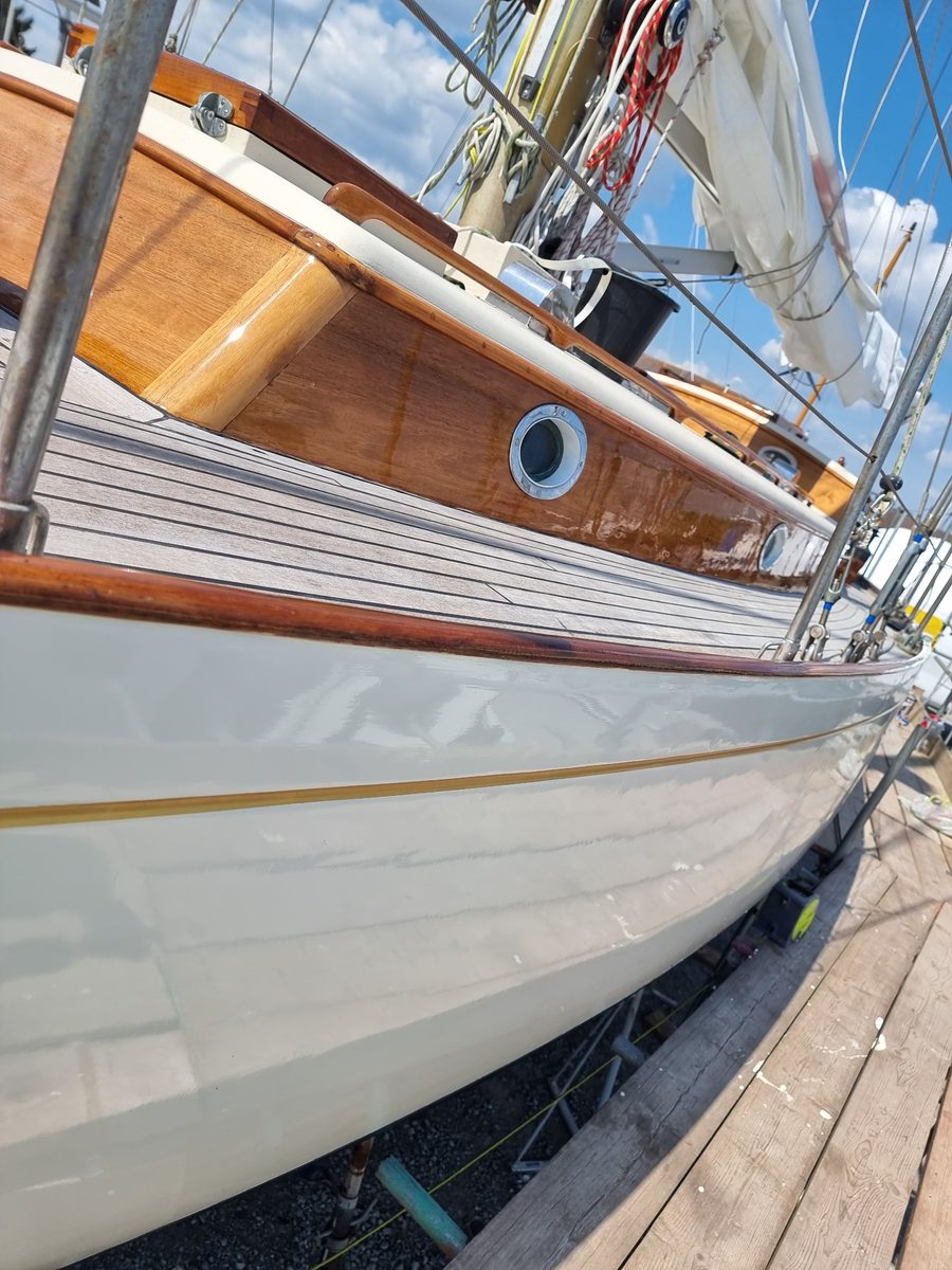 Zircon ashore: mirror-gloss cream topsides, gold cove line, varnished toe rail and coachroof above a laid teak deck